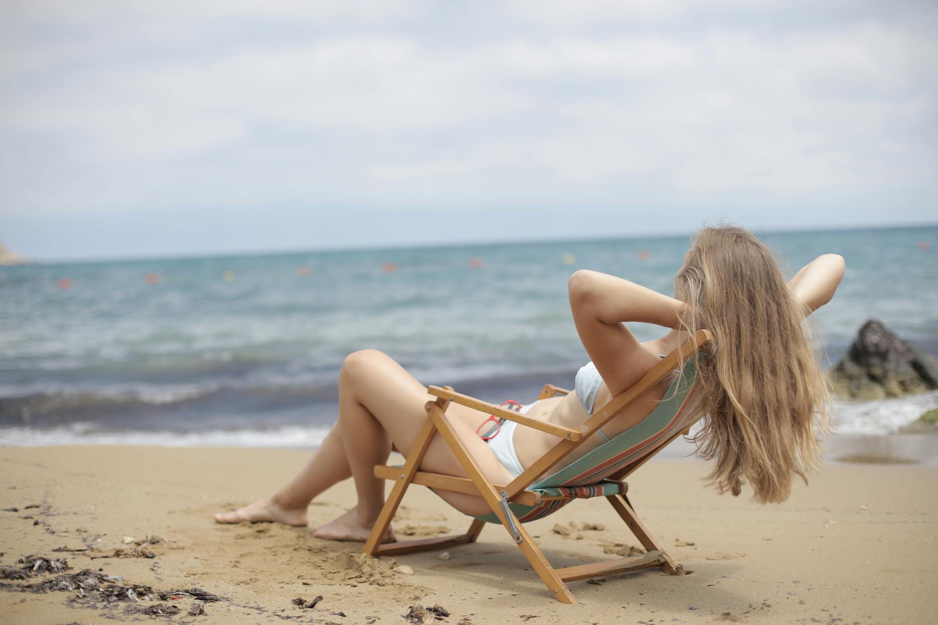 Frau Im Blauen Bikini Sitzt Auf Braunem Hölzernen Klappstuhl Am Strand